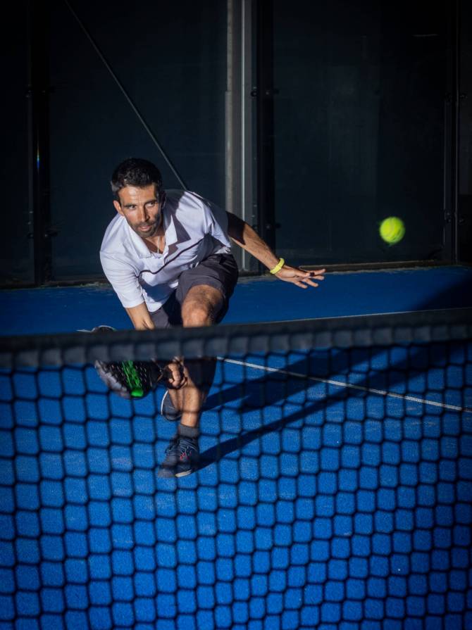 Sporty european man in white t-shirt playing padel tennis indoor